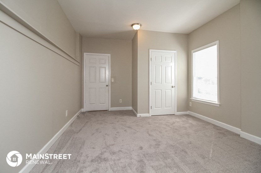 a bedroom with two doors and a carpeted floor