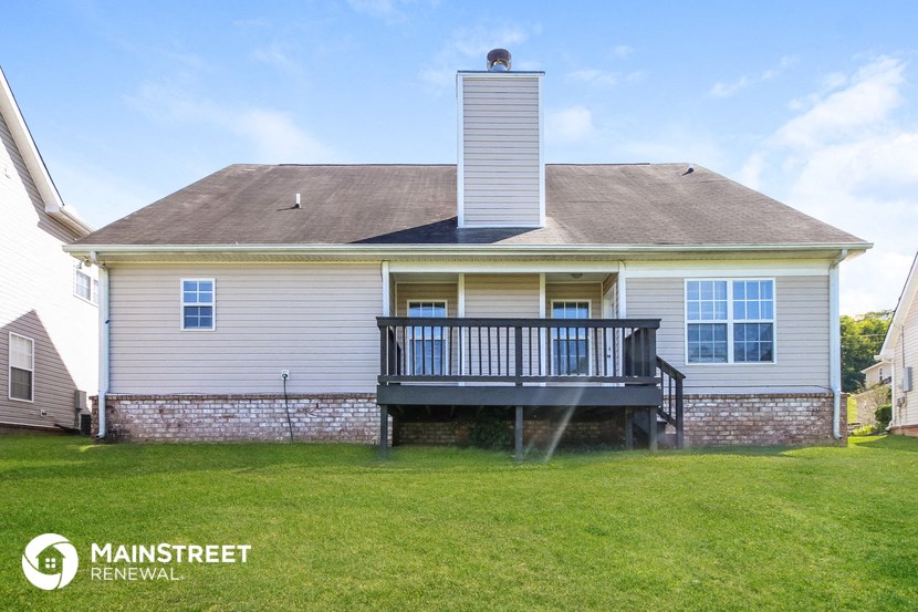 the back of a white house with a deck on the side