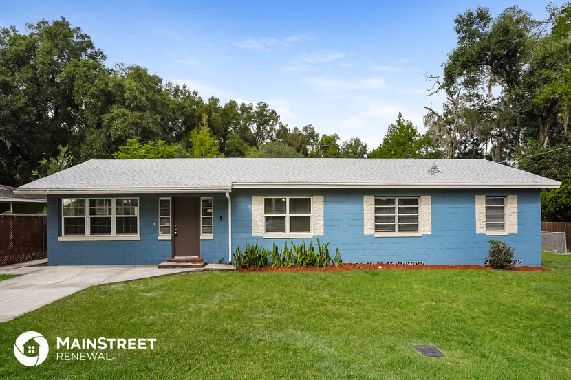 a blue house with a green lawn and trees