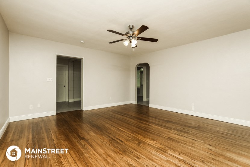 an empty living room with wood flooring and a ceiling fan