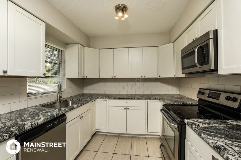 a white kitchen with marble counter tops and white cabinets