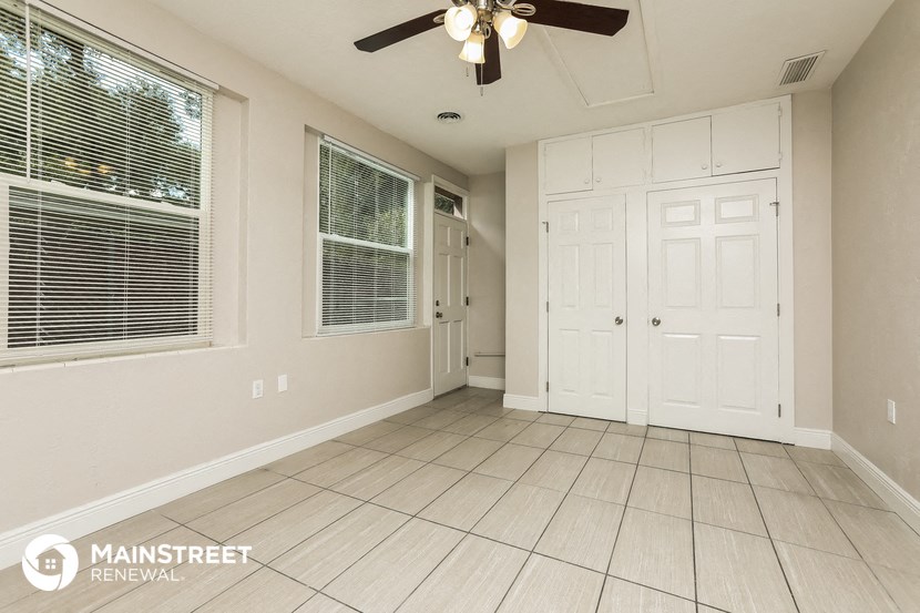 the living room of a home with white doors and a ceiling fan