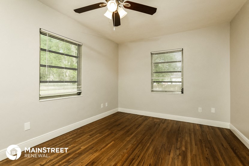 the spacious living room with hardwood floors and a ceiling fan