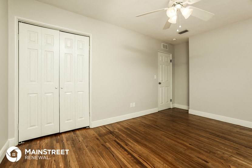 the living room of an apartment with wood flooring and a ceiling fan