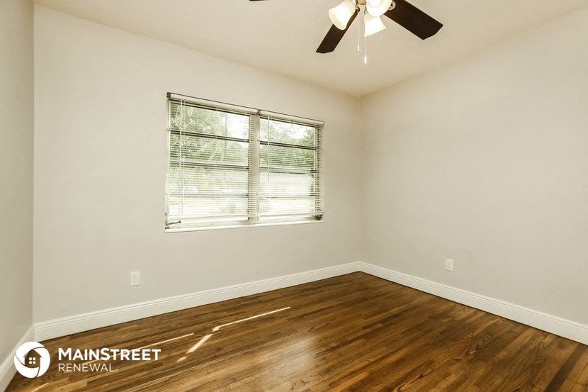 the spacious living room with hardwood flooring and a window
