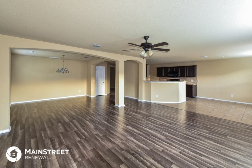 a living room and kitchen with wood flooring and a ceiling fan