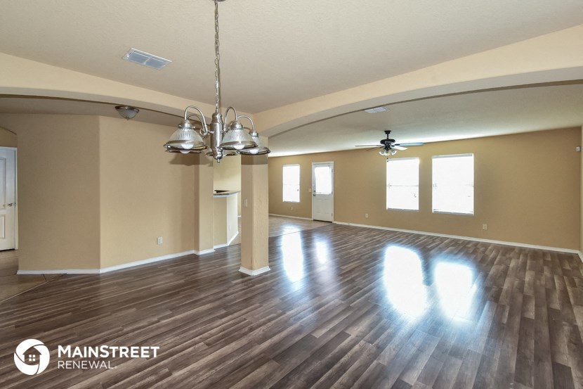 an empty living room with hardwood floors and a chandelier