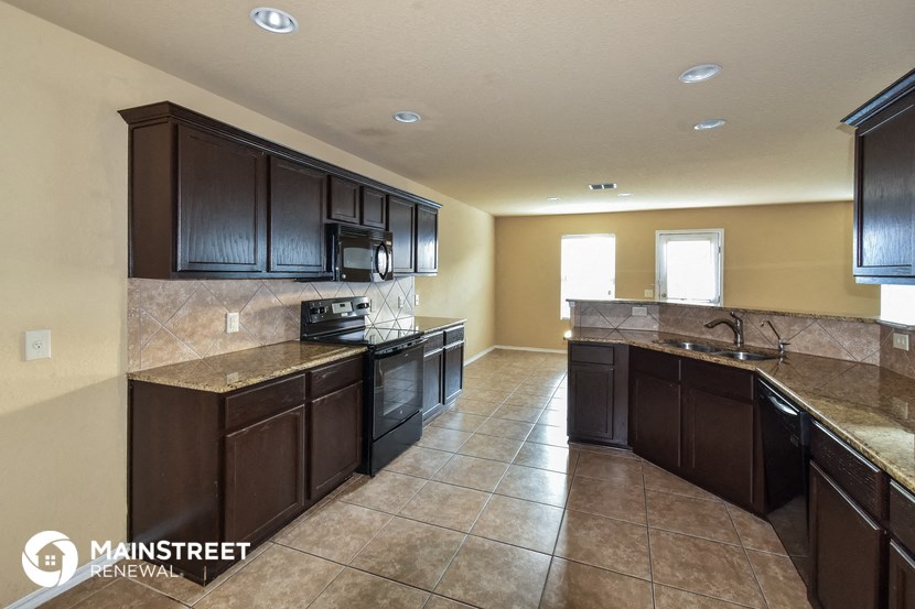 a kitchen with dark wood cabinets and tile flooring and counters