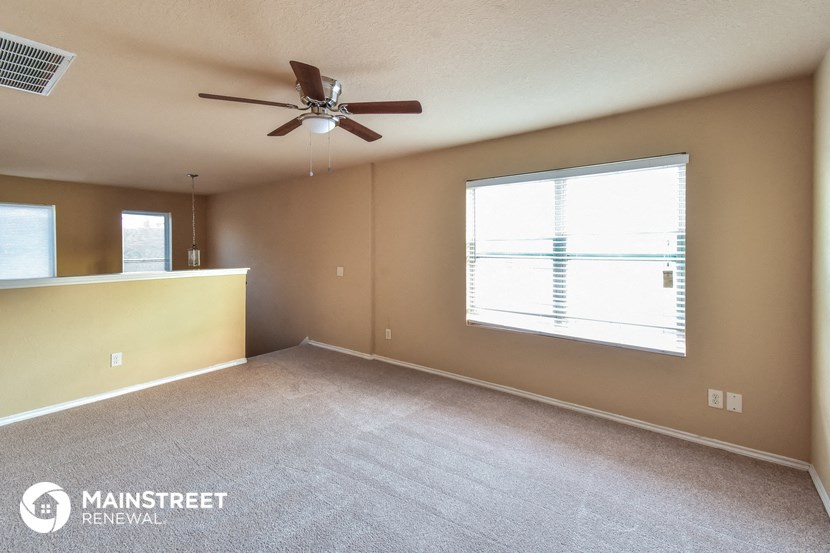 an empty living room with a ceiling fan and a large window