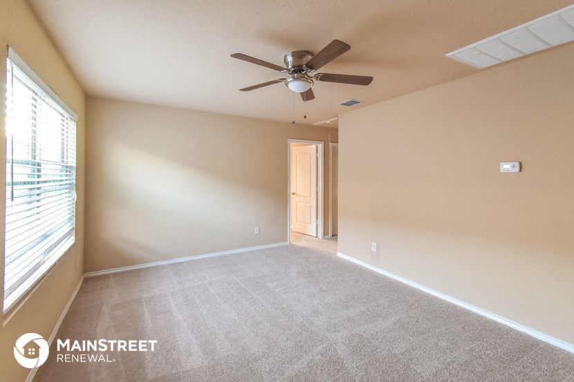 the living room is spacious and has a ceiling fan