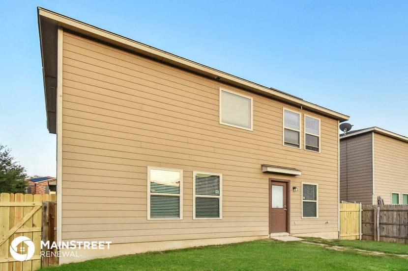 the front of a house with a yard and a wooden fence