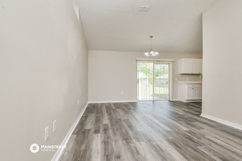 the living room and kitchen of an apartment with wood flooring