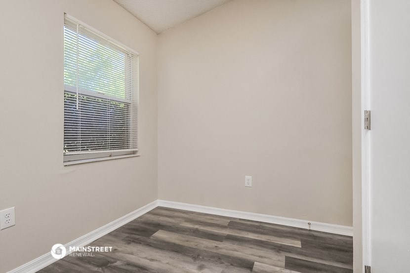 the interior of a bedroom with wood flooring and a window