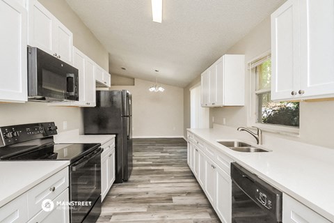 a white kitchen with black appliances and white cabinets