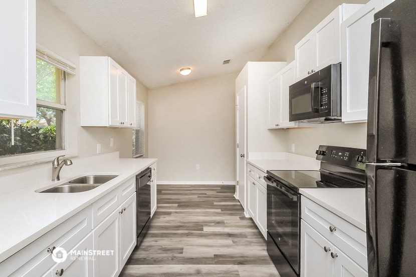 a kitchen with white cabinets and black appliances and a window