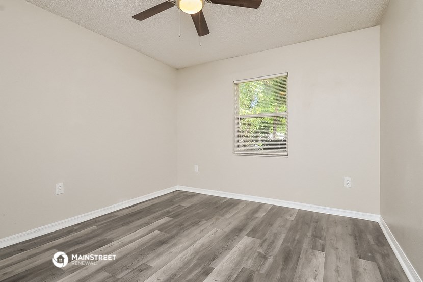 the spacious living room with wood flooring and a ceiling fan