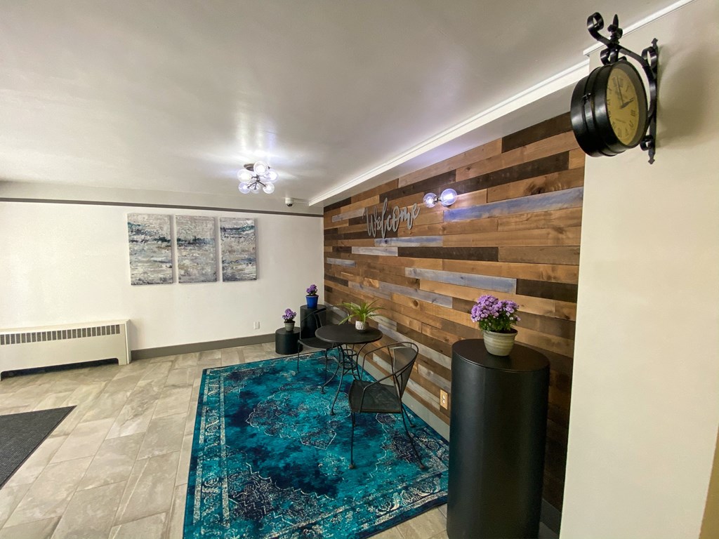 a living room with a blue rug and a wood wall