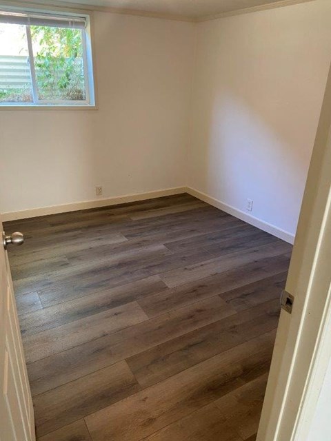 A room with wooden flooring and a window.