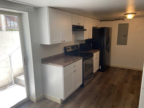 A kitchen with white cabinets and a black refrigerator.