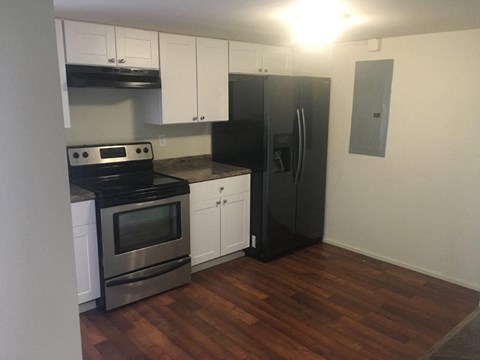 A kitchen with a black fridge and stove top oven.