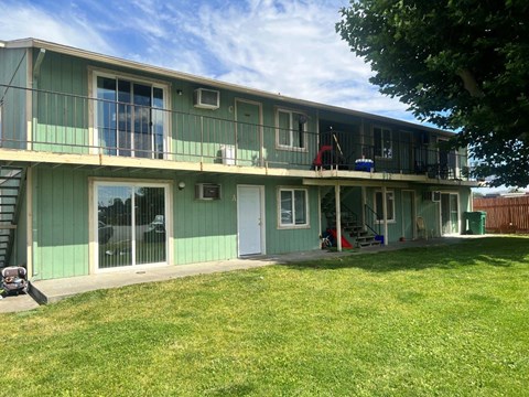 A green and white two story house with a lawn in front.