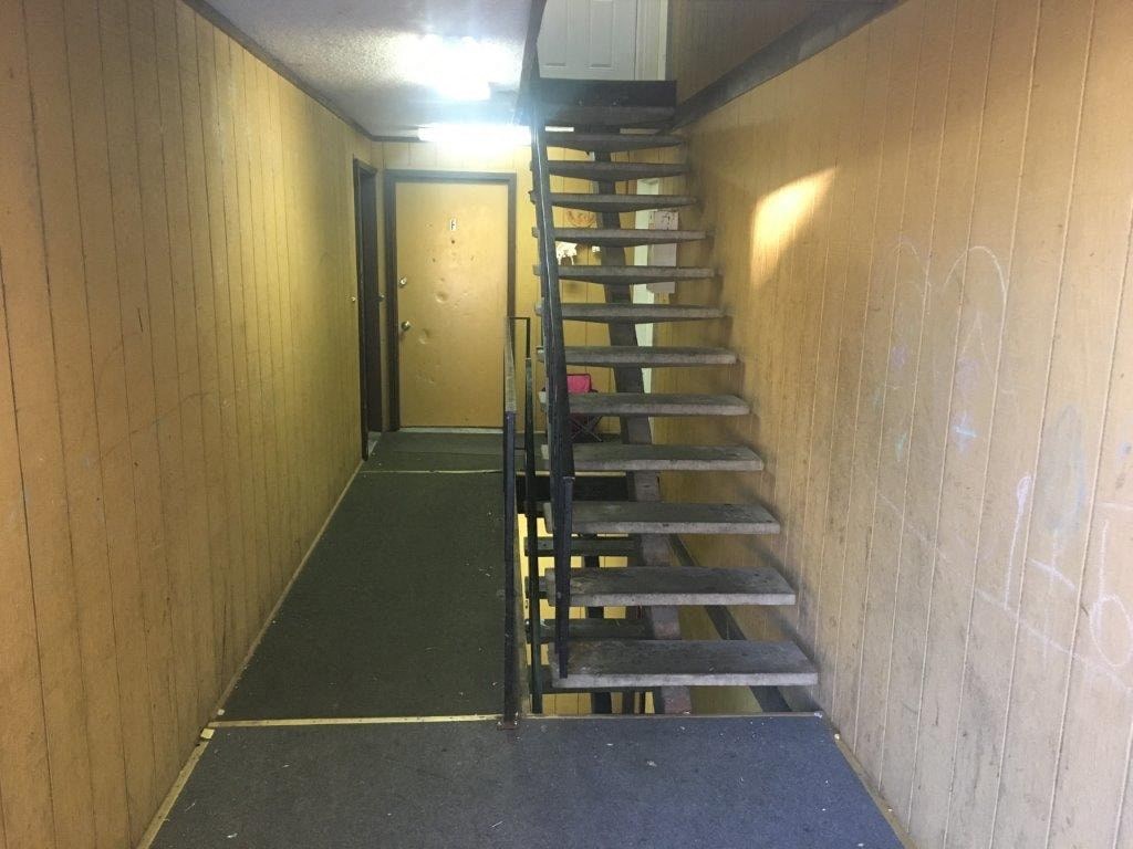 A staircase with a black railing and steps leading to a door.