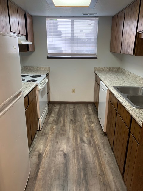 A kitchen with white appliances and wooden floors.
