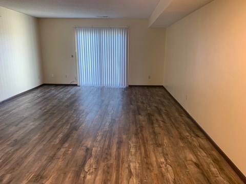 A room with wooden flooring and a window with blinds.