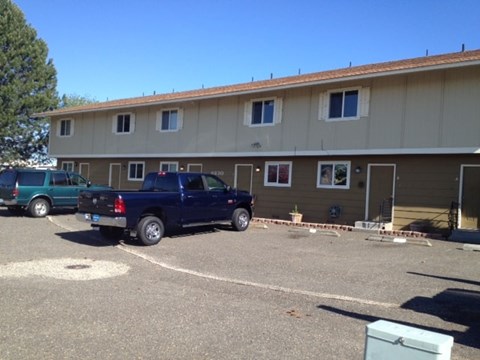 A blue pickup truck is parked in a parking lot in front of a building.