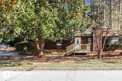 a house with a porch and a tree in front of it