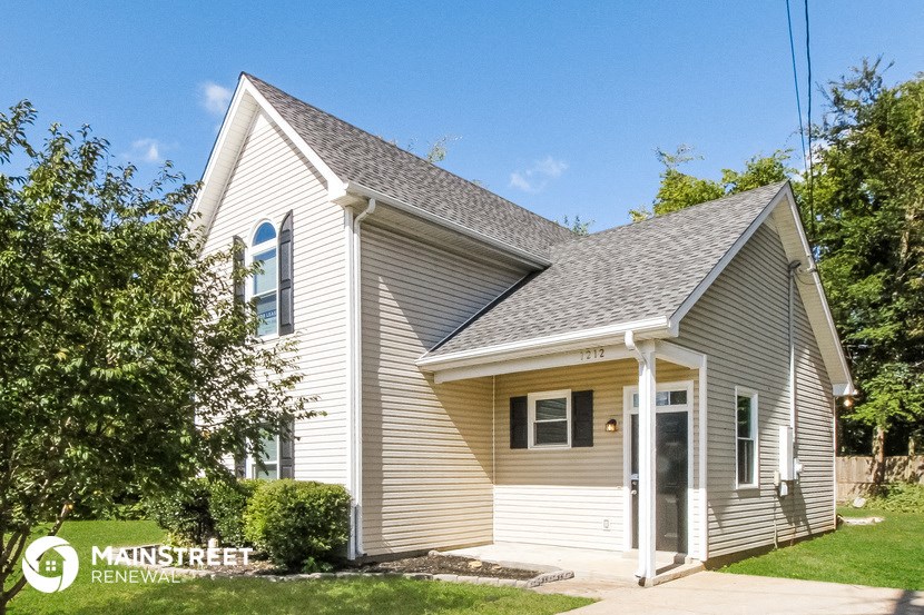 a small white house with a gray roof and a driveway