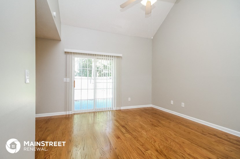 the spacious living room with wood flooring and sliding glass door to the pool