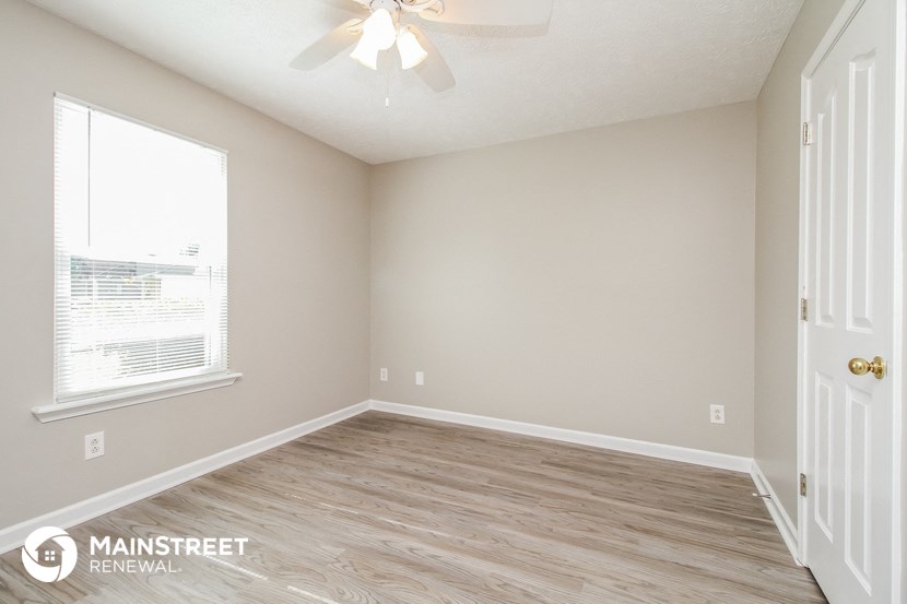 the spacious living room with wood flooring and a ceiling fan