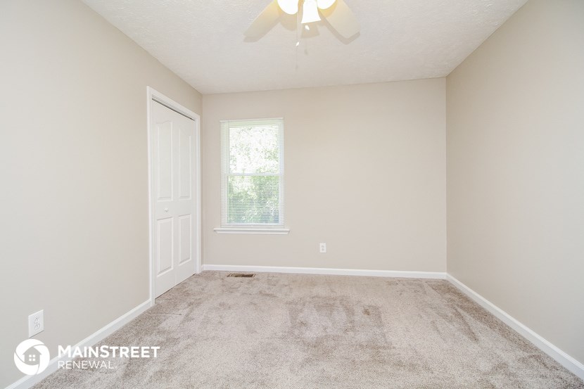the upstairs bedroom has a carpeted floor and a ceiling fan