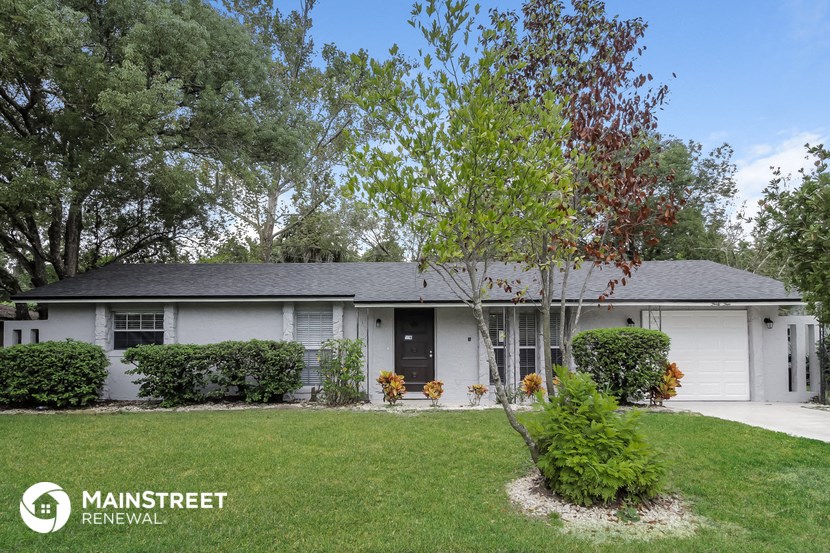 a white house with a lawn and a tree