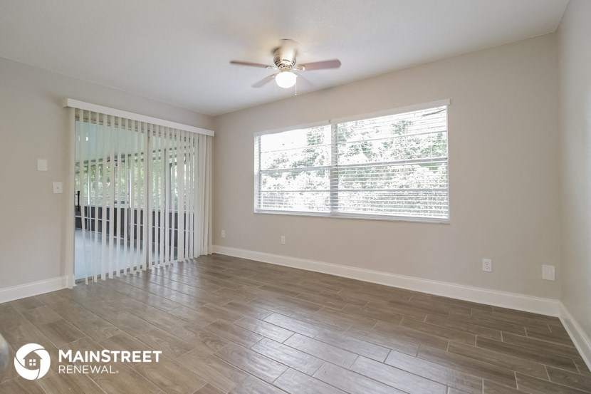 an empty living room with a ceiling fan and a large window
