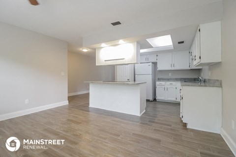the kitchen and living room of an apartment with white cabinets