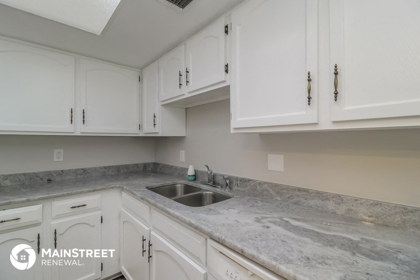 a white kitchen with marble counter tops and white cabinets