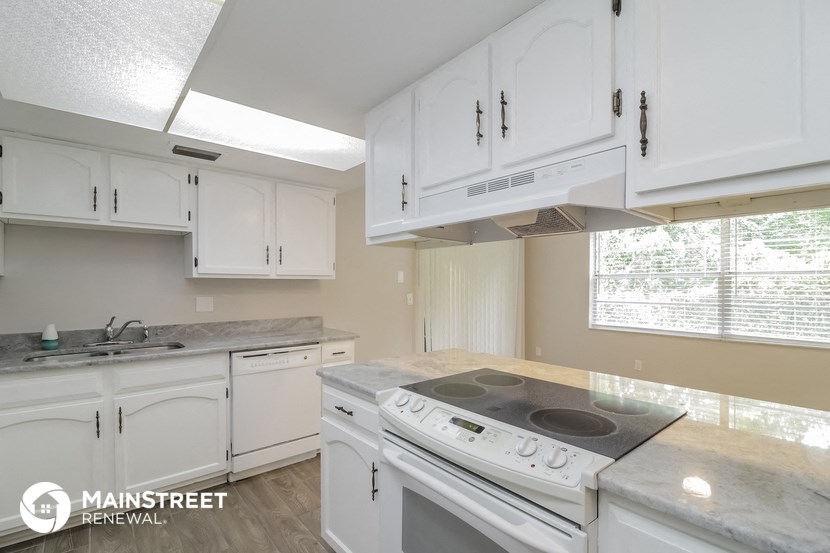 an image of a kitchen with white cabinets and a stove and a sink