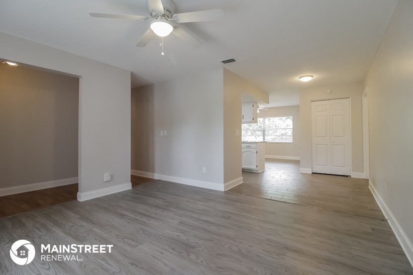 the living room and dining room of an empty house with a ceiling fan