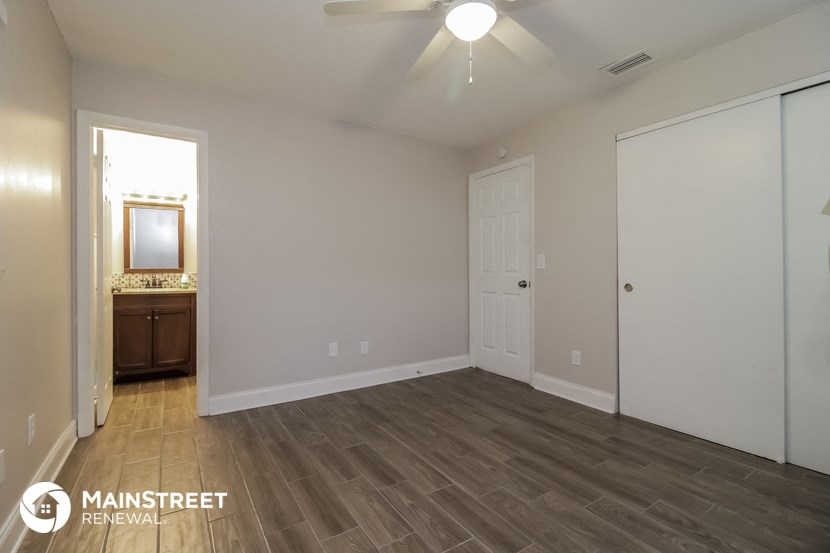 the spacious living room with wood flooring and a ceiling fan