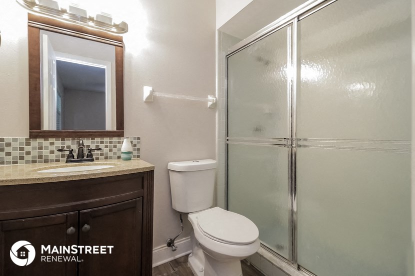 a bathroom with a shower toilet and sink and a mirror