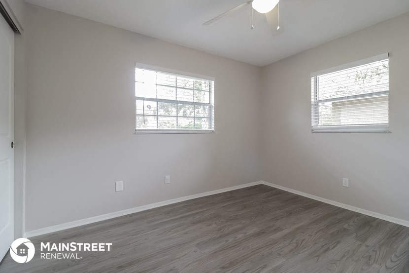 the interior of an empty room with wood flooring and two windows