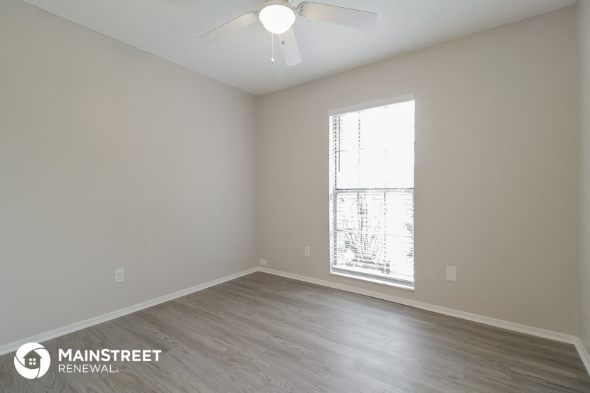 the spacious living room with a large window and wood flooring