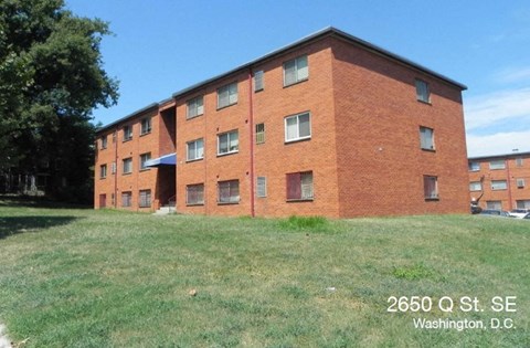 A red brick building with the address 2650 Q St. SE, Washington, D.C. on a sunny day.