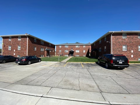 A parking lot in front of a brick building with two cars parked.