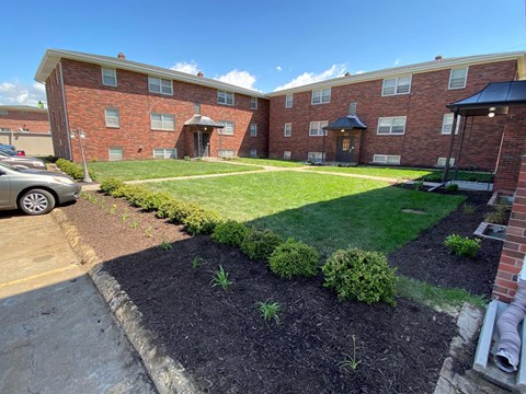 A brick apartment building with a green lawn in front.