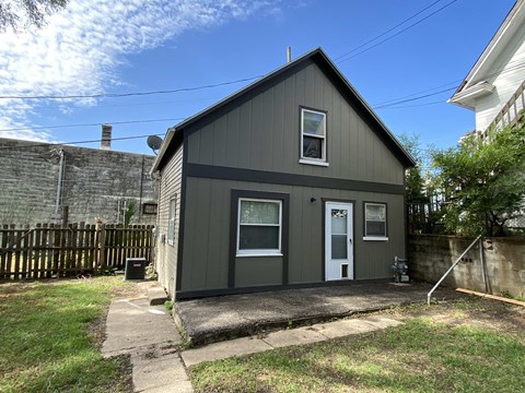 the exterior of a small gray house with a white door
