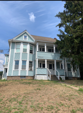 an old house with blue and white siding and a lawn