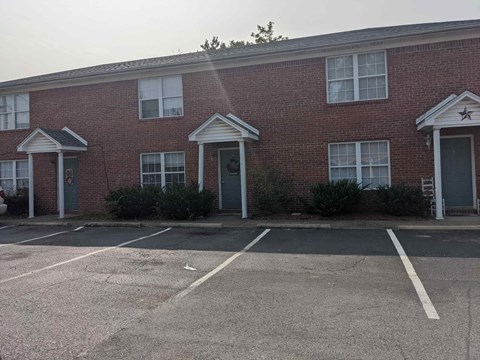 A red brick building with a parking lot in front.